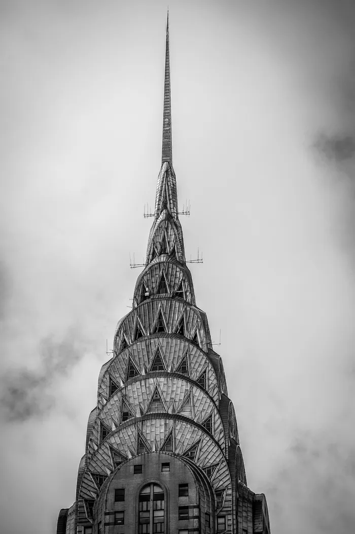 The spire of a Manhattan skyscraper against a cloudy sky