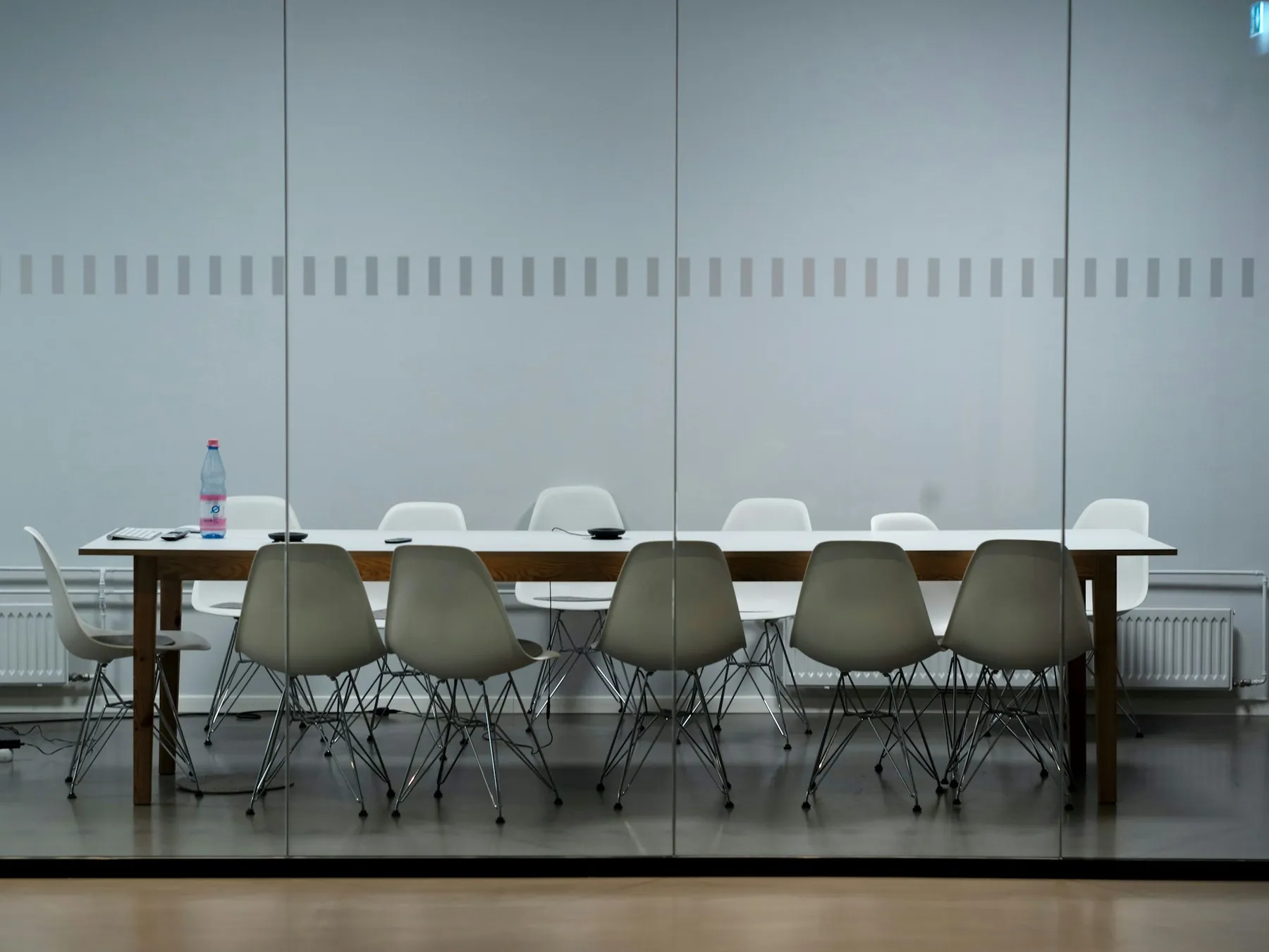 A plain meeting table set with chairs in a quiet room