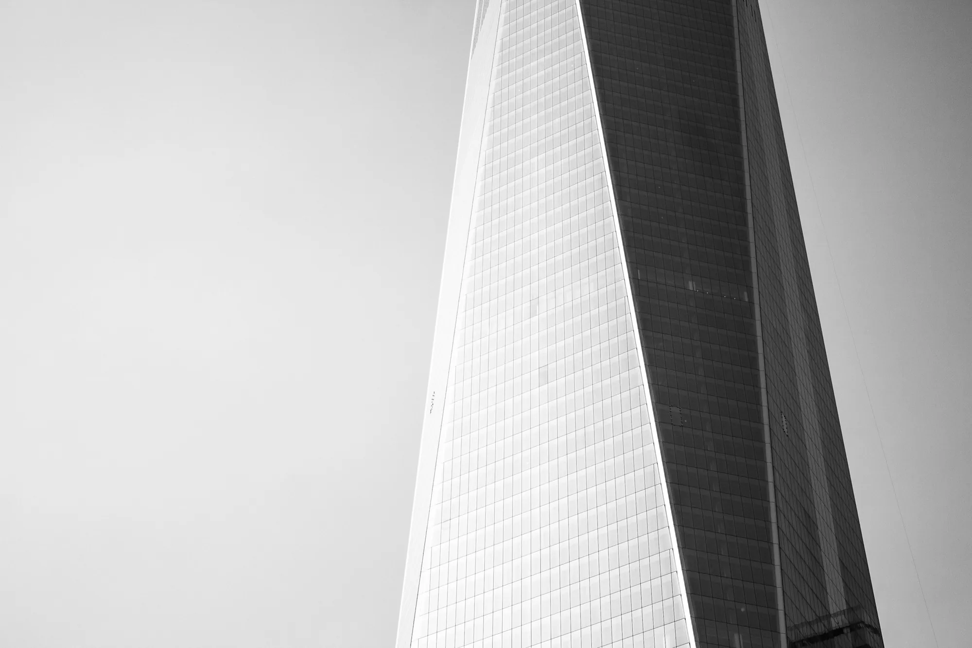 The tapering edge of a glass skyscraper against a white sky